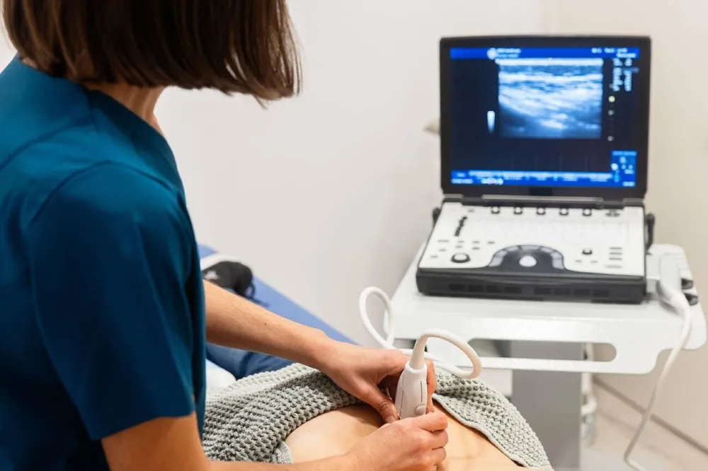 Transductor de ultrasonido apoyado sobre el abdomen durante un estudio